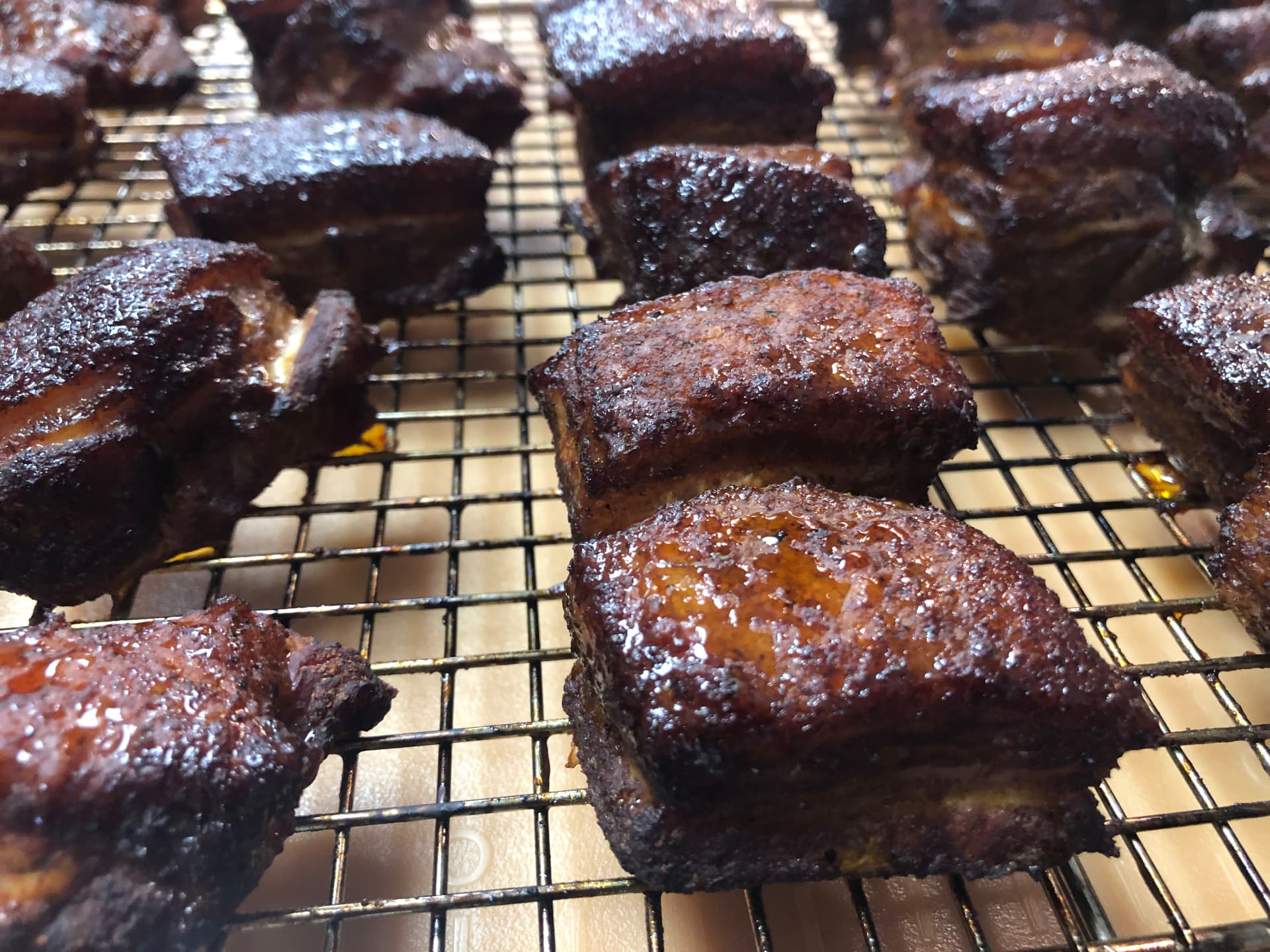 Fresh smoked pork belly burnt ends resting on a rack