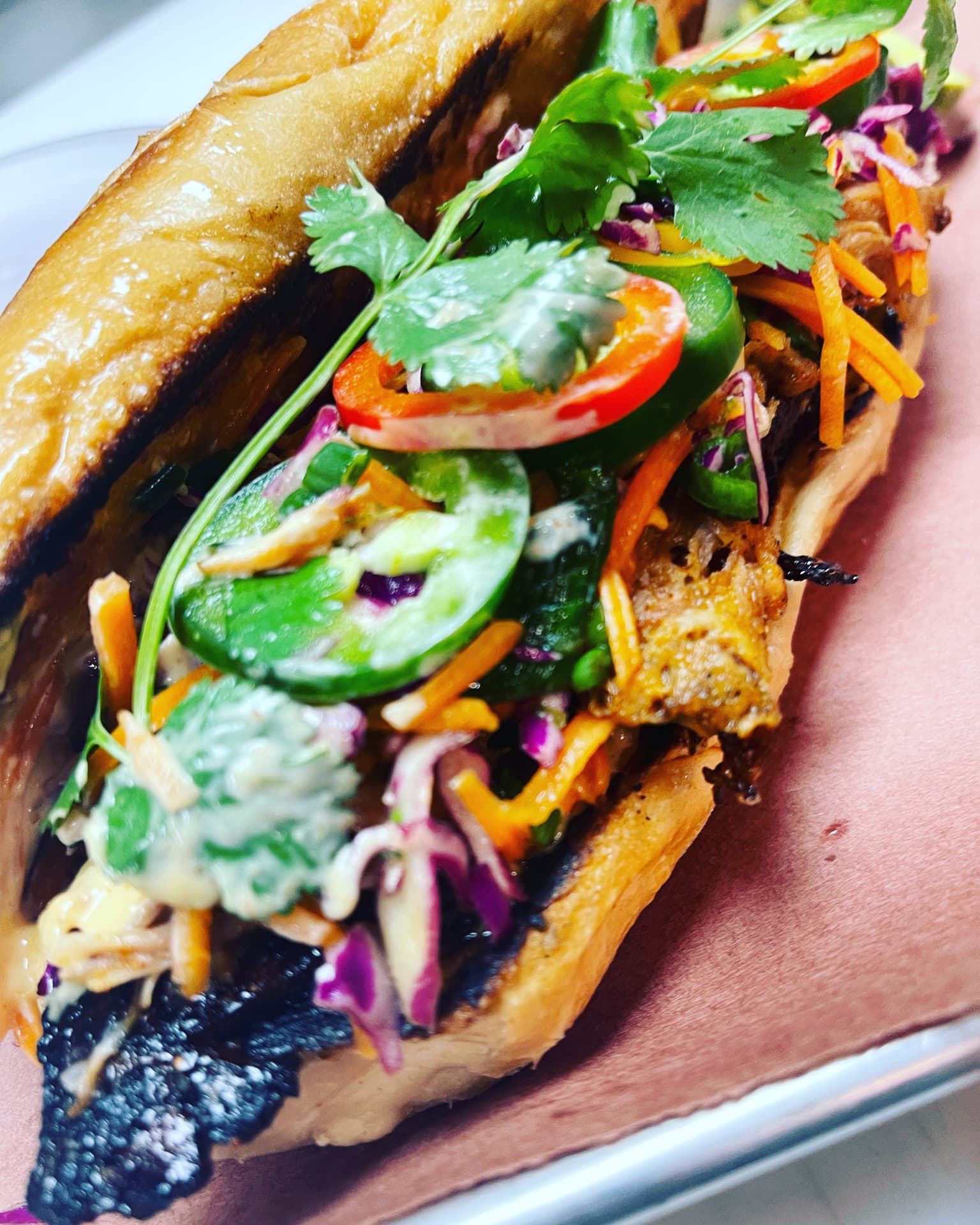 Smoked meat sandwich with crisp vegetables, jalapeño and cilantro