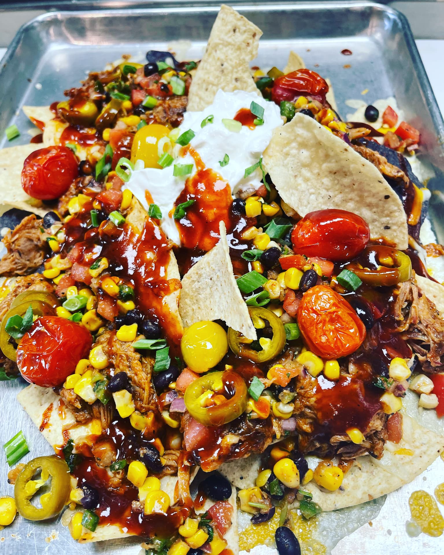Loaded barbecue nachos with corn, peppers and tomatoes