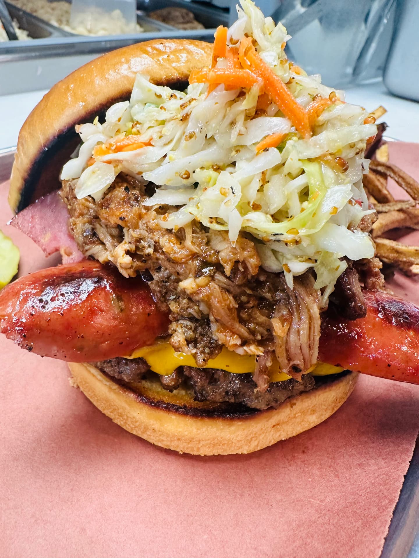 Loaded barbecue burger with smoked sausage, pulled pork and vinegar slaw