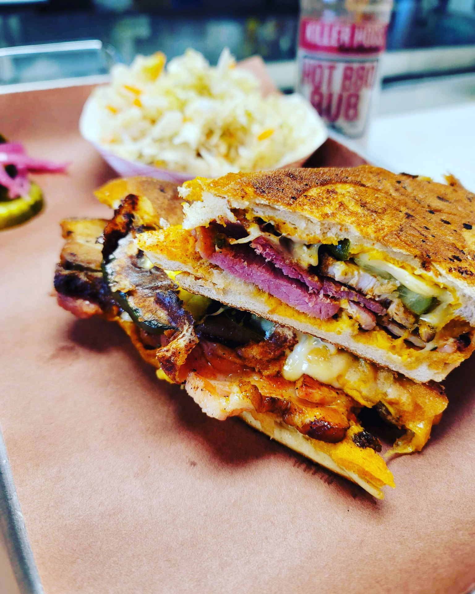 Stacked smoked meat sandwich with chicken, brisket, cheese and pickles